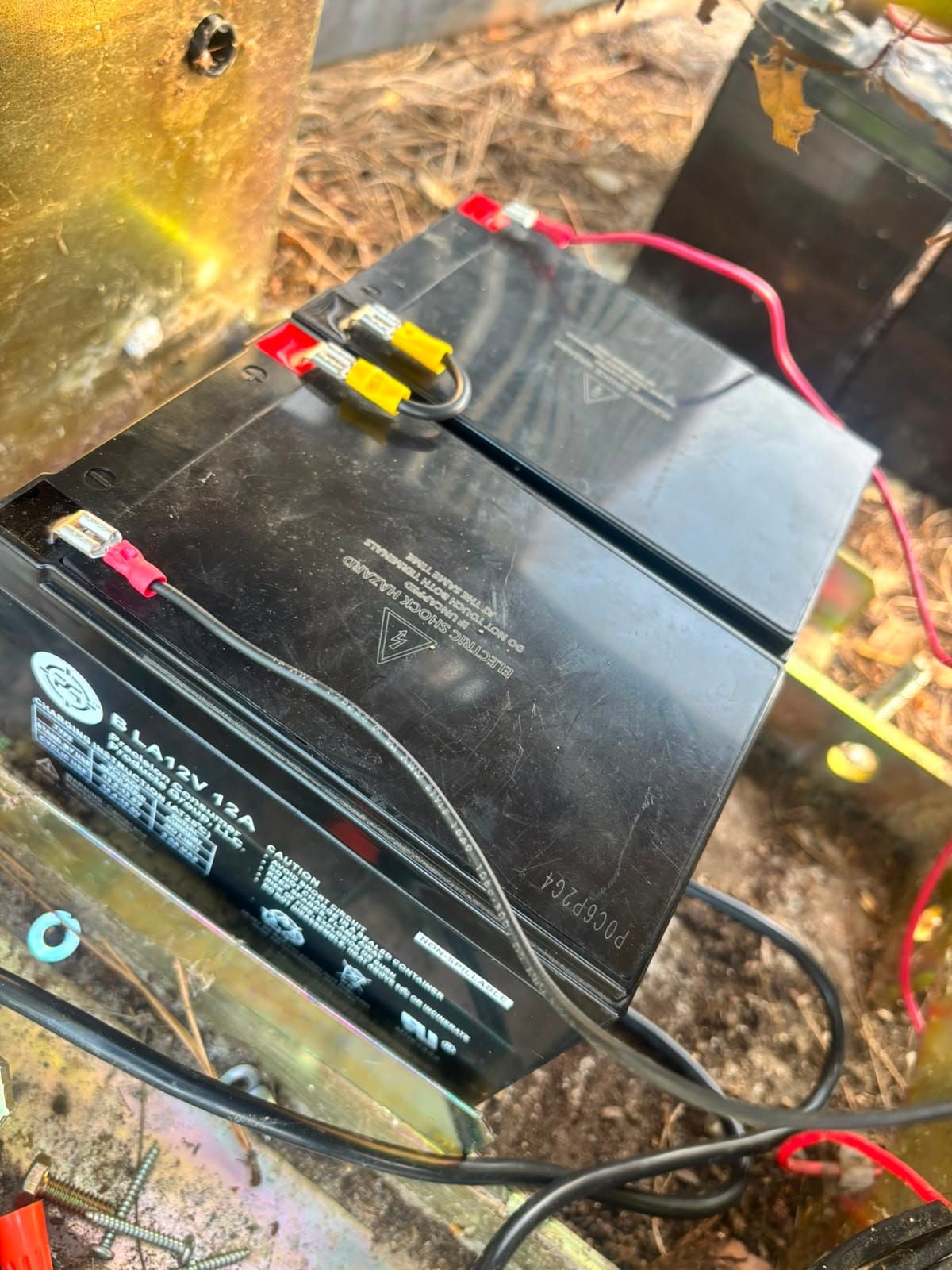 Two sealed lead acid backup batteries wired into a gate operator enclosure, with red and black leads connected to the terminals