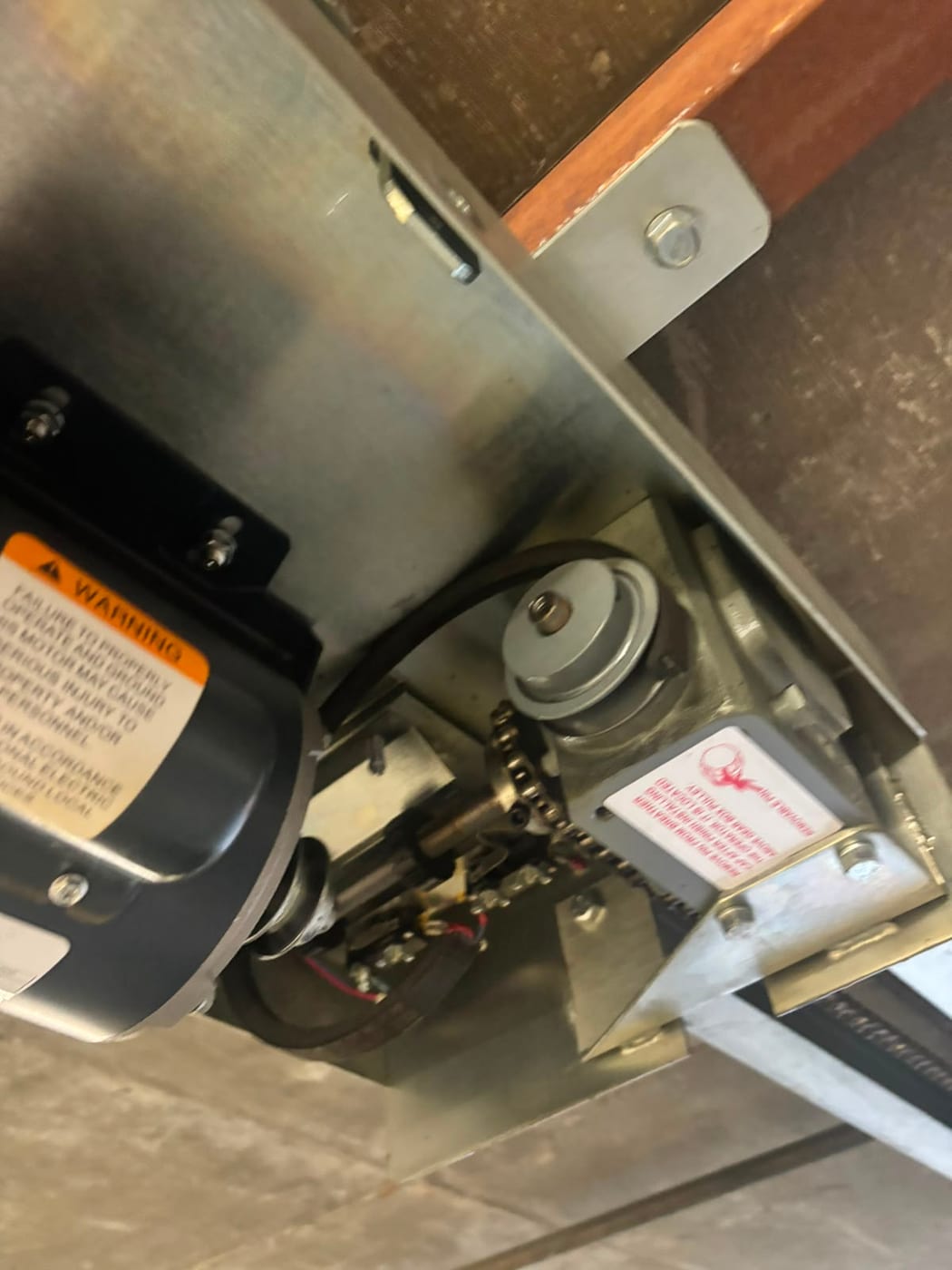 Close view of a commercial rolling door operator showing the motor, chain drive and gear reduction unit mounted above the door