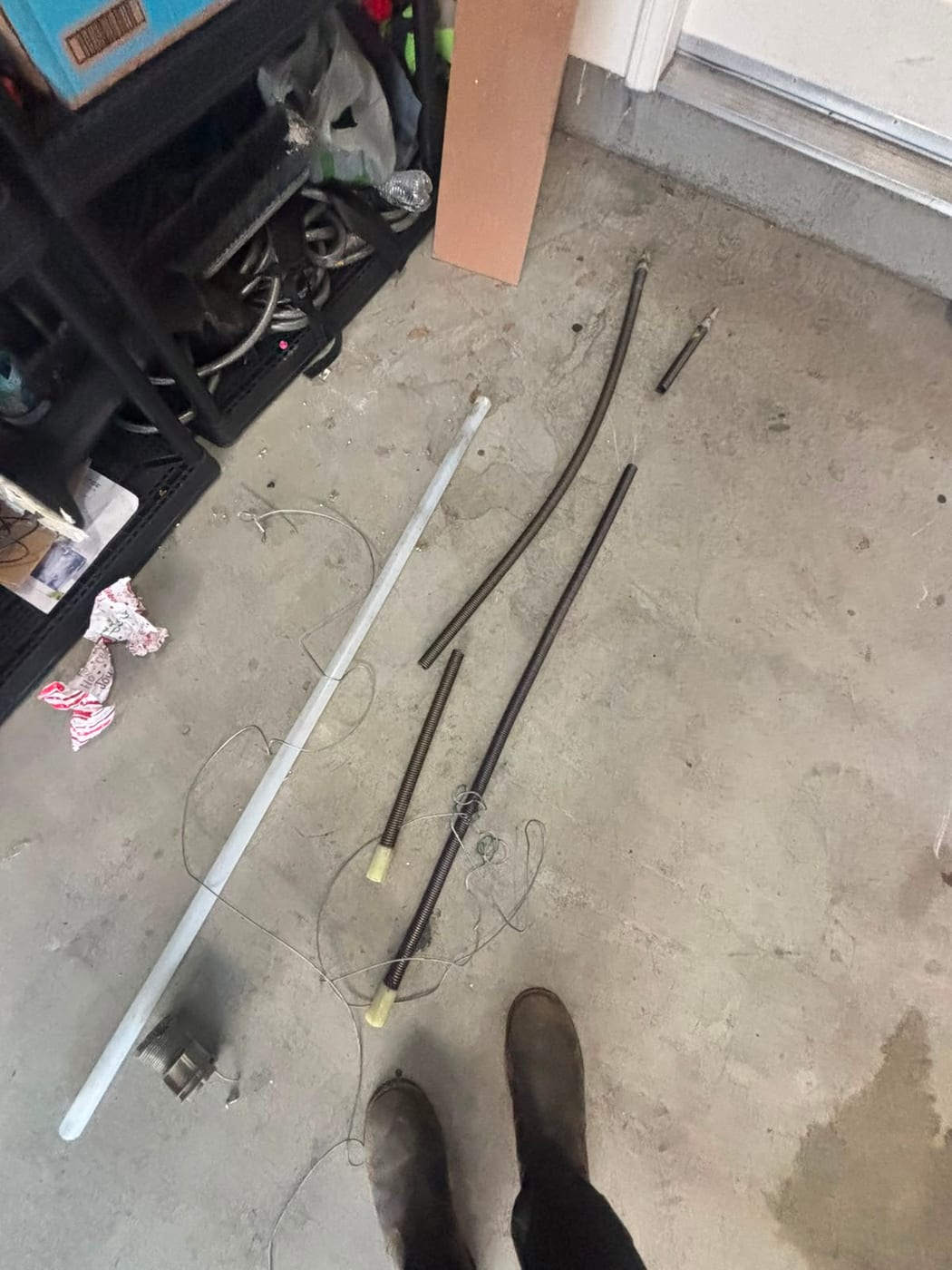 Old garage door springs, lift cables and the torsion bar laid out on a garage floor after removal